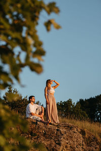 Young adult couple, man and woman enjoying beautiful sunset outdoors in the nature	
