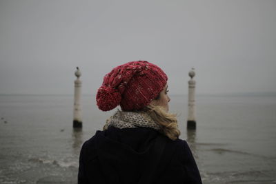 Rear view of woman wearing warm clothing while standing against sea