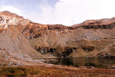 Scenic view of lake by rock formation against sky