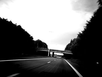 Road amidst trees against sky in city