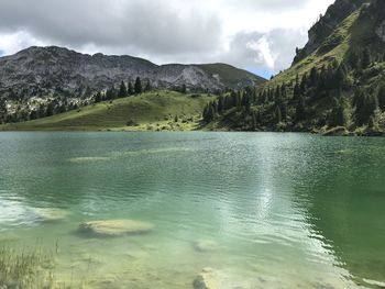 Scenic view of lake by mountains against sky