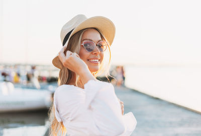 Portrait of smiling young woman wearing hat standing outdoors