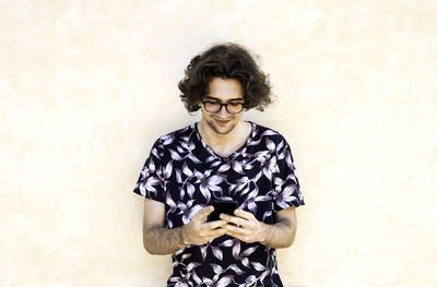 Portrait of young man standing against wall