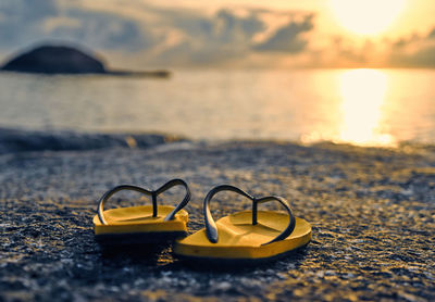 Motor scooter on beach against sky during sunset