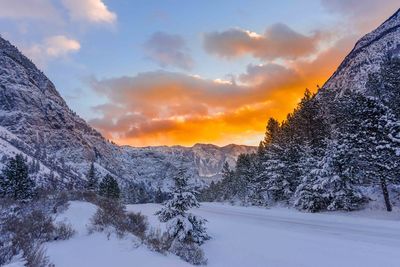 Snow covered landscape against sky during sunset