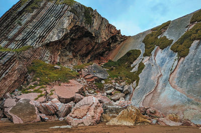 View of rocky mountains against sky on beach