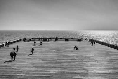 People on promenade by sea against sky