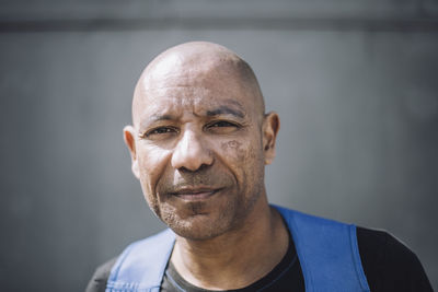 Portrait of bald mature construction worker against wall