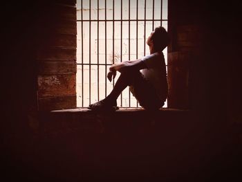 Side view of man sitting by window