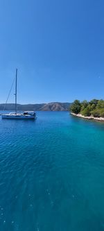 Sailboats in sea against clear blue sky