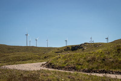 Wind turbines on field against clear sky