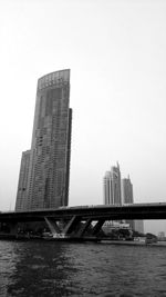 Bridge over river by buildings against sky in city