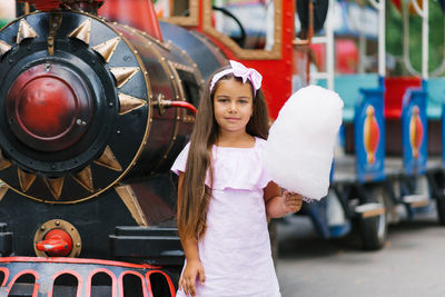 Child girl in an amusement park in the summer eats cotton candy and smiles happily