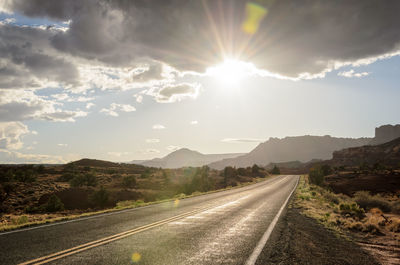Road leading towards mountains against sky