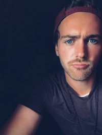 Close-up portrait of young man over black background