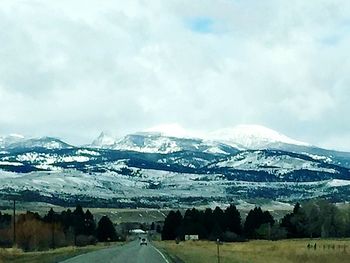 Snow covered landscape against cloudy sky