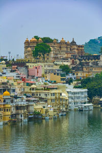 Buildings by river against sky