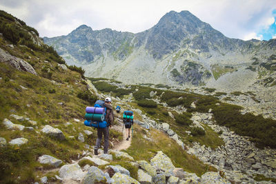 Rear view of backpackers walking on mountain