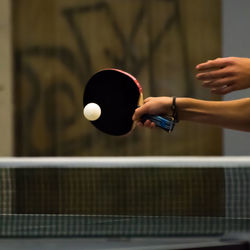 Cropped hand playing table tennis in court