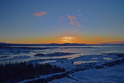 Scenic view of snow covered land against sky during sunset