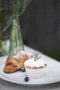 Close-up of cupcake with croissant on plate