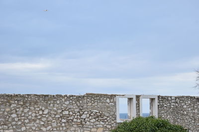 Stone wall of building against sky