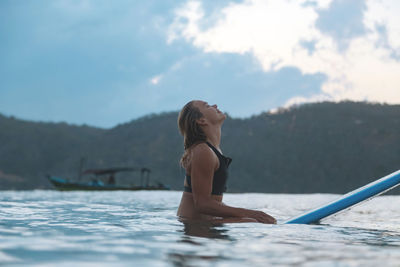 Female surfer in the ocean at sunset