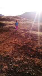 Rear view of woman on field against bright sun