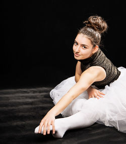 Portrait of woman sitting against black background