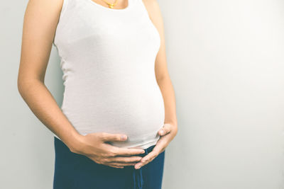 Midsection of woman touching hair against white background