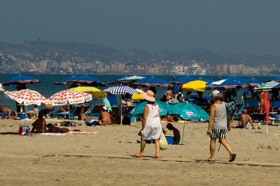 People at beach against clear sky