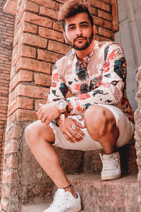 Portrait of young man crouching on staircase