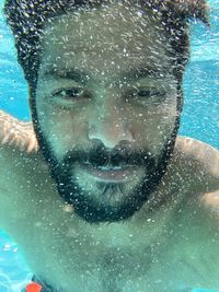 Close-up portrait of shirtless smiling man swimming undersea