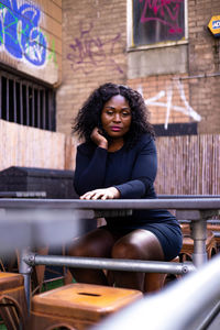 Portrait of young woman sitting on railing