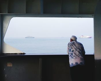 Rear view of a man standing by sea against sky