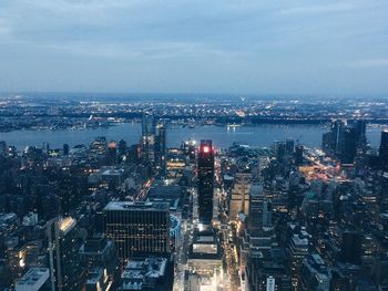 River amidst illuminated cityscape against sky at dusk