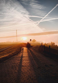 Man on railroad track against sky during sunset