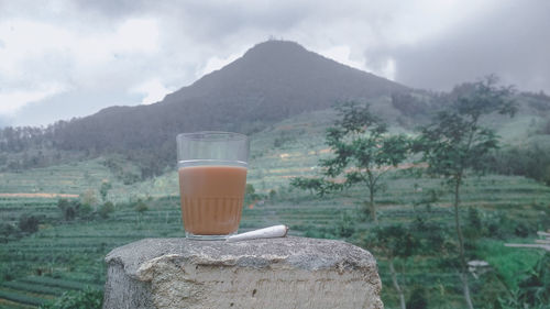 Close-up of drink on rock against sky