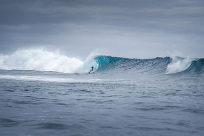 Man surfing on sea cloudy sky