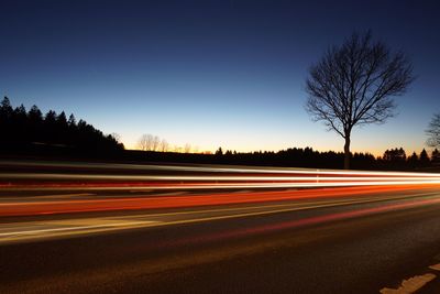 Light trails on road against clear sky at night