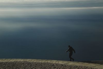 Woman standing by sea against sky