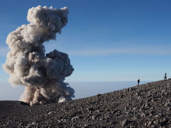 Smoke emitting from volcanic mountain against clear sky