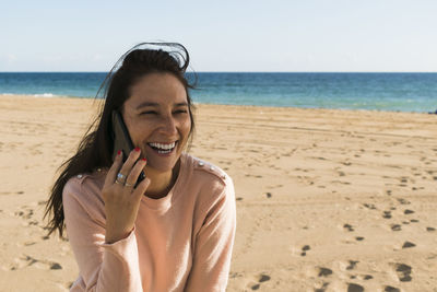 Young woman using phone on beach