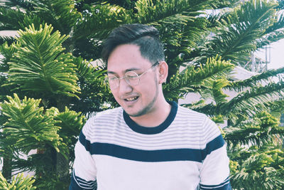 Portrait of smiling young man against palm trees