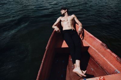 High angle view of young man sleeping in boat on lake