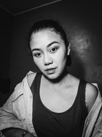 Portrait of young woman against wall at home