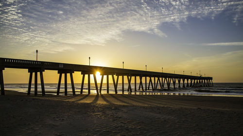 Pier over sea against sky during sunset