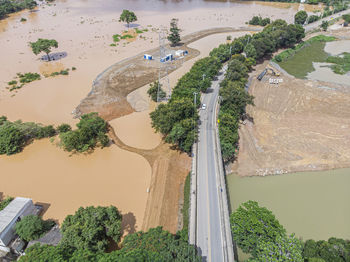 River flooding due to rain causes large mud next to a dam that prevents the rivers from meeting 