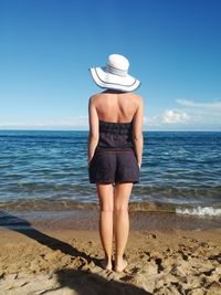 Rear view of woman standing by sea against sky