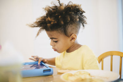 Close-up of boy using digital tablet while sitting at table